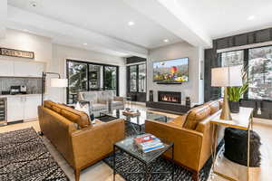 Living room featuring a glass covered fireplace, light wood-style floors, wine cooler, and recessed lighting