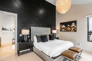 Bedroom featuring a decorative wall, light wood-type flooring, and a chandelier
