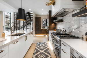 Kitchen with double oven range, modern cabinets, tasteful backsplash, light countertops, and recessed lighting