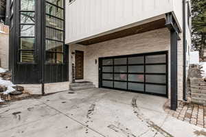 Property entrance with concrete driveway, an attached garage, and board and batten siding