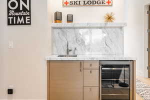 Indoor wet bar with wine cooler and backsplash
