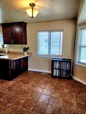 Kitchen with dark brown cabinets, a textured ceiling, and light countertops