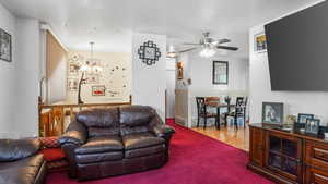 Living room featuring a chandelier, a ceiling fan, and carpet floors
