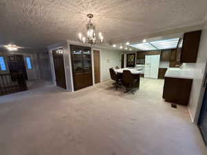 Dining area with a chandelier, a textured ceiling, light colored carpet, and ornamental molding
