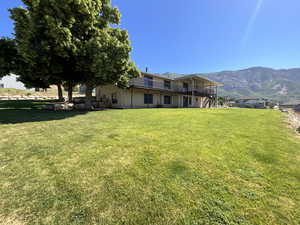 Back of property featuring a lawn, a deck with mountain view, and stairs