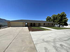 Ranch-style home with brick siding, concrete driveway, an attached garage, and a front lawn