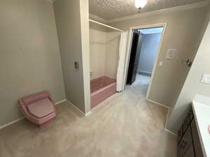 Full bathroom featuring shower / bath combination with curtain, vanity, crown molding, and a textured ceiling