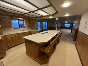 Kitchen featuring light carpet, a center island, a wainscoted wall, light countertops, and a breakfast bar area