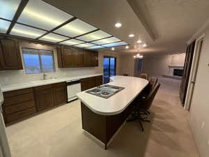 Kitchen with white dishwasher, electric stovetop, light colored carpet, dark brown cabinets, and recessed lighting