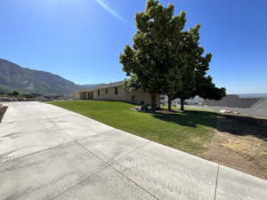 View of grassy yard featuring driveway and a mountain view