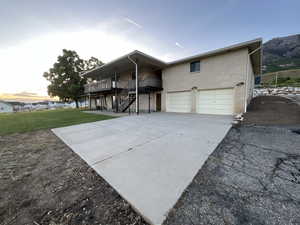 Back of house with an attached garage, concrete driveway, a lawn, a trex deck, and brick siding