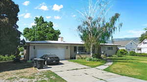 Ranch-style house featuring brick siding, driveway, a garage, a front yard, and a chimney