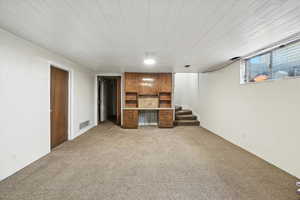 Unfurnished living room featuring light colored carpet and stairs