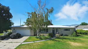 Ranch-style home featuring brick siding, a garage, concrete driveway, and a front yard