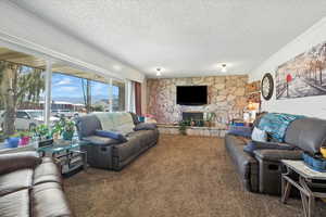 Living room featuring carpet, a textured ceiling, and a fireplace