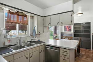 Kitchen featuring dishwasher, a peninsula, light countertops, and dark wood-style flooring