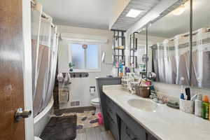 Bathroom featuring wood finished floors, vanity, and shower / tub combo