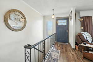 Foyer entrance featuring hardwood / wood-style flooring, a textured ceiling, and crown molding