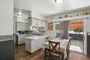 Kitchen with stainless steel microwave, light countertops, dark wood-type flooring, and a peninsula