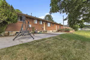 Back of property with brick siding, a patio, and a garden