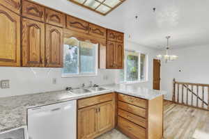 Kitchen with dishwasher, a peninsula, light countertops, and plenty of natural light
