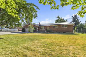 Single story home featuring a garage, driveway, a chimney, a gate, and solar panels