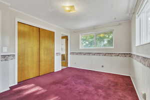Unfurnished bedroom with carpet flooring, crown molding, and a closet