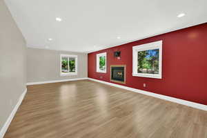 Empty room with light wood finished floors, recessed lighting, and a glass covered fireplace