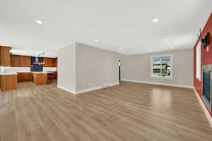 Unfurnished living room featuring recessed lighting, light wood-type flooring, and a glass covered fireplace