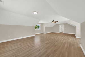 Additional living space with light wood-type flooring, a ceiling fan, and lofted ceiling