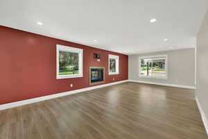 Unfurnished living room featuring wood finished floors, a glass covered fireplace, and recessed lighting