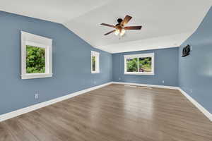 Spare room featuring a ceiling fan, lofted ceiling, and wood finished floors