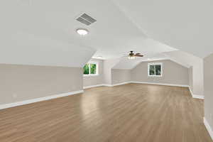 Bonus room with plenty of natural light, light wood-style floors, vaulted ceiling, and ceiling fan