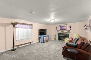 Carpeted living area featuring a fireplace and a textured ceiling