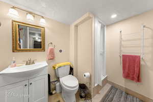 Full bath with a textured ceiling, vanity, shower / bathtub combination with curtain, and recessed lighting