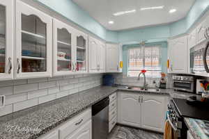 Kitchen featuring stainless steel appliances, white cabinetry, glass insert cabinets, backsplash, and recessed lighting