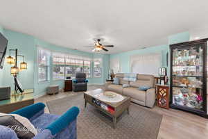 Living room with light wood finished floors and a ceiling fan