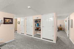 Hall featuring carpet flooring and a textured ceiling