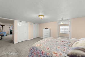 Carpeted bedroom featuring multiple closets and a textured ceiling