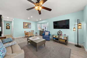 Living area with light wood-style floors, ceiling fan, and recessed lighting