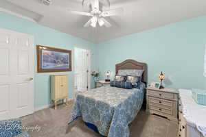 Bedroom with light colored carpet, attic access, and a ceiling fan