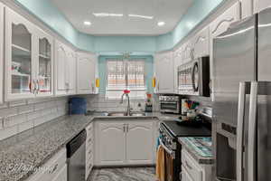 Kitchen featuring stainless steel appliances, white cabinetry, tasteful backsplash, and recessed lighting