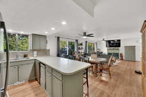 Kitchen with a peninsula, light countertops, a kitchen breakfast bar, ceiling fan, and decorative backsplash