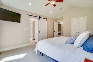 Bedroom with a barn door, lofted ceiling, light carpet, recessed lighting, and a ceiling fan