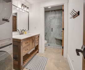 Bathroom with vanity, a marble finish shower, and concrete flooring