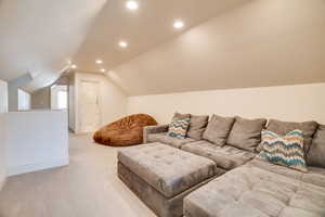 Living room featuring light carpet, vaulted ceiling, and recessed lighting