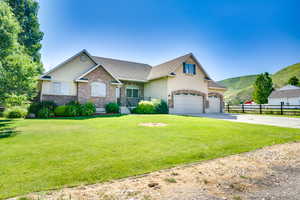 View of front of home featuring driveway, brick siding, a mountain view, a garage, and stucco siding