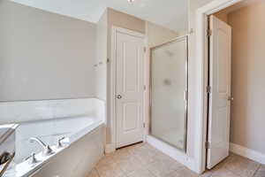 Full bath with tile patterned flooring, a stall shower, and a bath