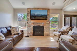Living room with wood finished floors, plenty of natural light, and a stone fireplace