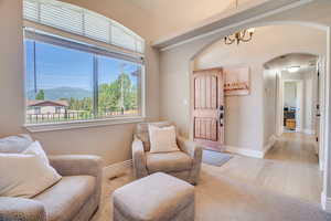 Living area featuring arched walkways, light wood-style flooring, and a chandelier